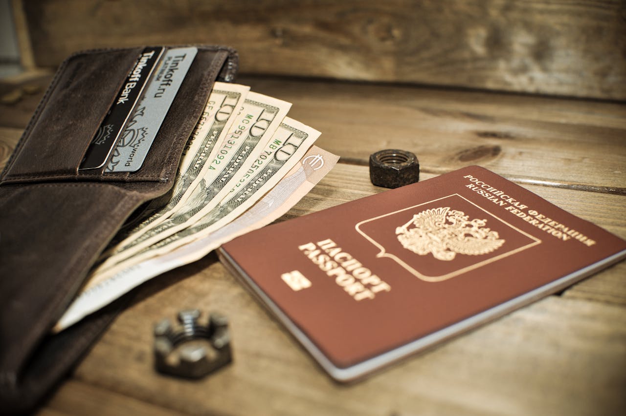 A wallet with cash, credit cards, and a Russian passport on a wooden table.