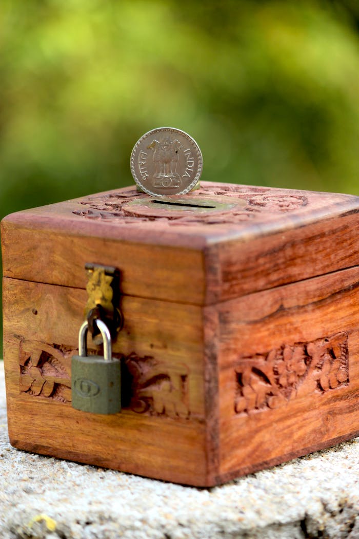 Wooden piggy bank with detailed carving and Indian coin, symbolizing savings and wealth.